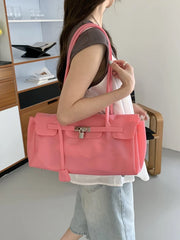 Pink PVC tote bag with silver hardware held by a person.