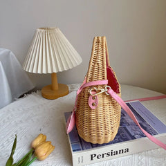 Wicker handbag with pink strap on a book next to a lamp and tulips