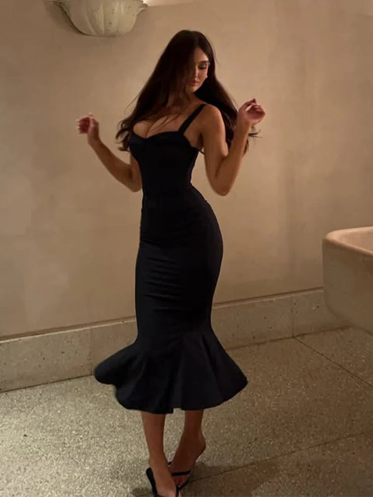Woman in a black dress standing in a bathroom.