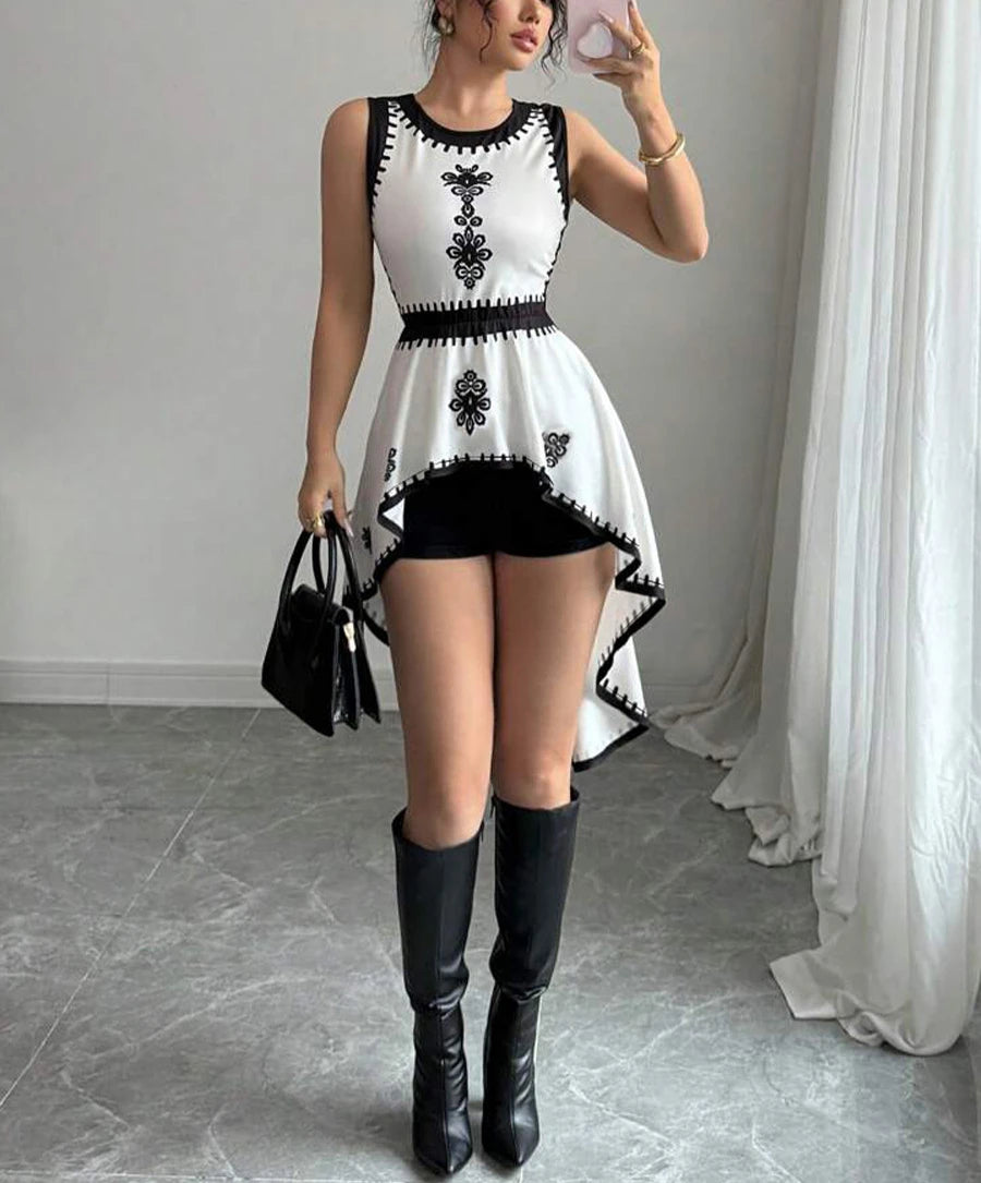 Woman wearing a white dress with black patterns and black knee-high boots in an indoor setting.