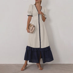 Woman wearing a white dress with navy accents against a plain background