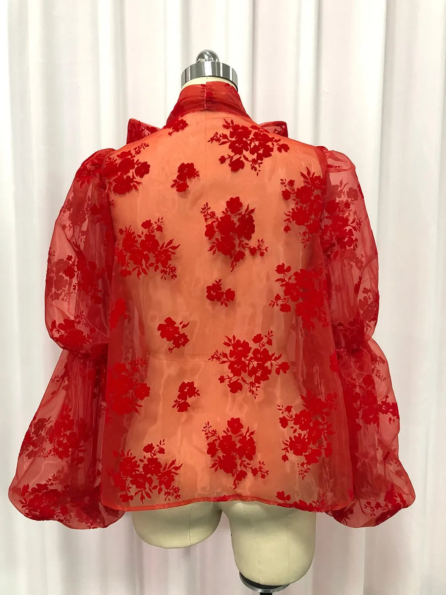 Red floral lace top on a mannequin against a white curtain background