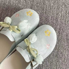 Light gray slippers with floral designs on a textured surface