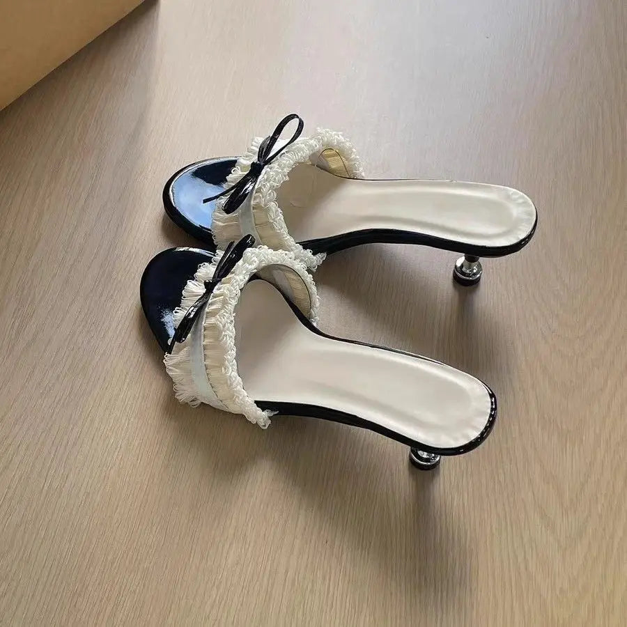 Top view of bow heeled slide sandal on wooden surface