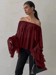 Woman wearing a burgundy off-shoulder top with ruffled sleeves against a plain background