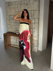 A woman walking in a stylish strapless maxi dress with a colorful print.