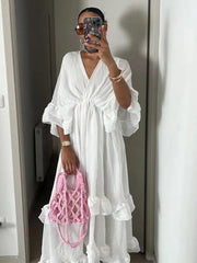 Person wearing a white dress holding a pink bag in front of a mirror.