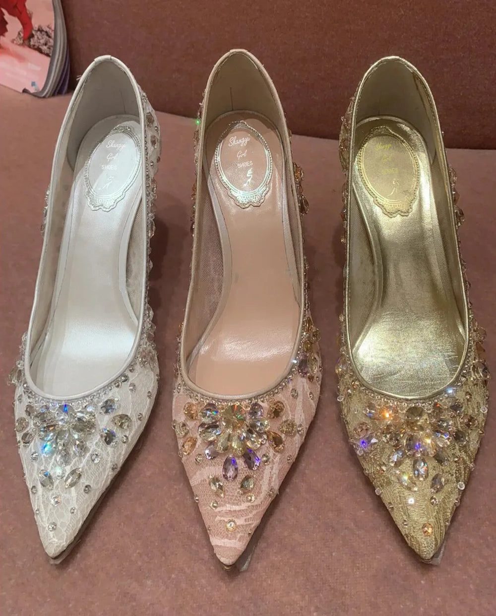 Three high-heeled shoes with embellishments on a brown surface