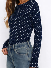 Navy blue long-sleeve top with white polka dots worn by a person against a white background