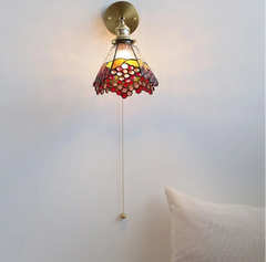 Decorative wall light fixture with stained glass shade on a plain background
