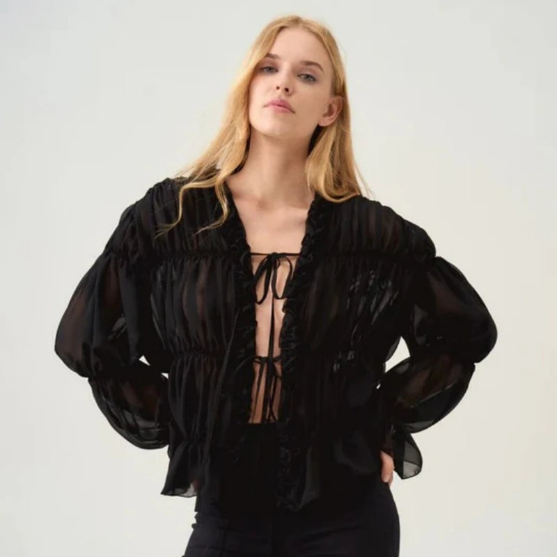 Woman wearing a black ruffled blouse against a plain background
