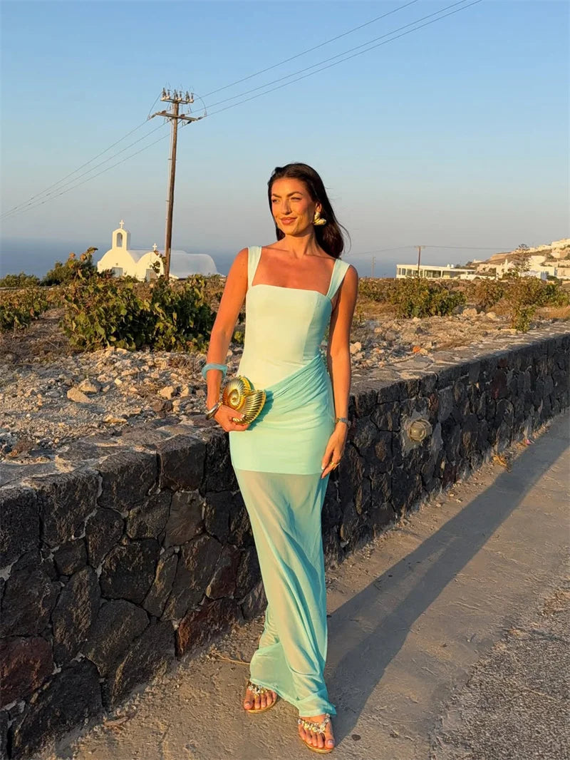 Woman in a light blue dress standing on a stone path with a scenic background
