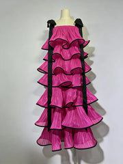 Pink ruffled dress with black accents on a mannequin against a white background