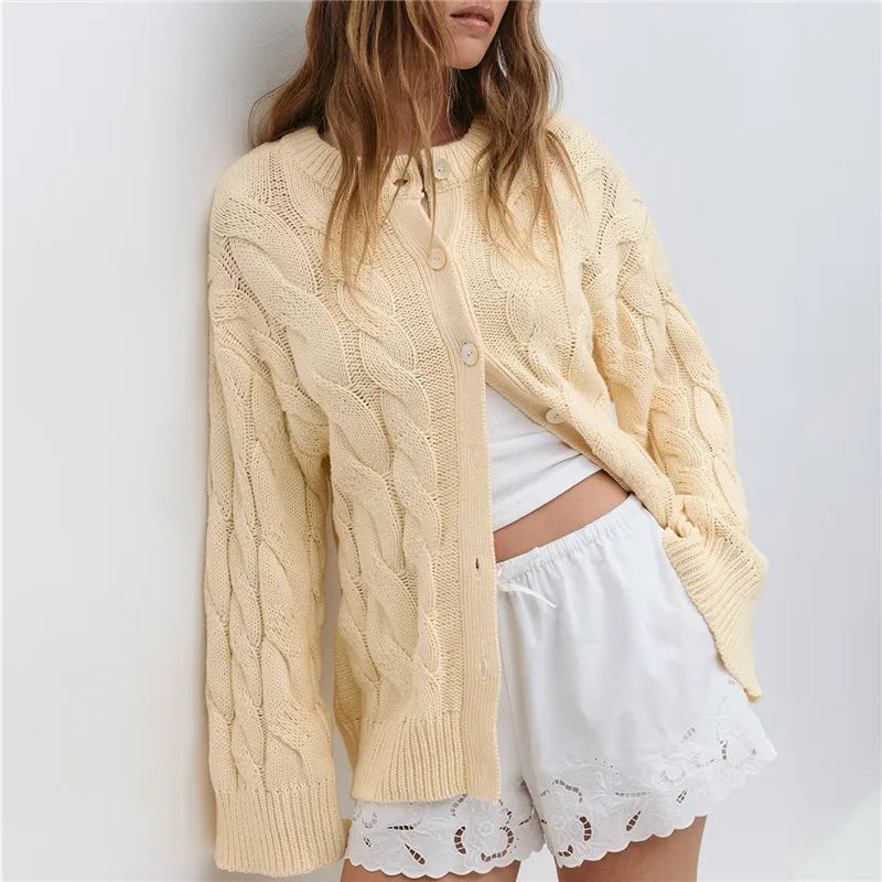 Woman wearing a light yellow cable knit cardigan over a white top and shorts 
