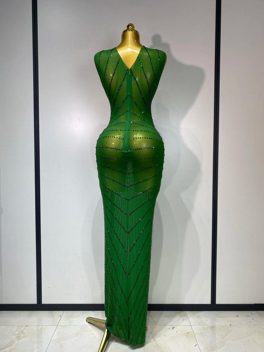 Green evening gown on a mannequin against a plain background