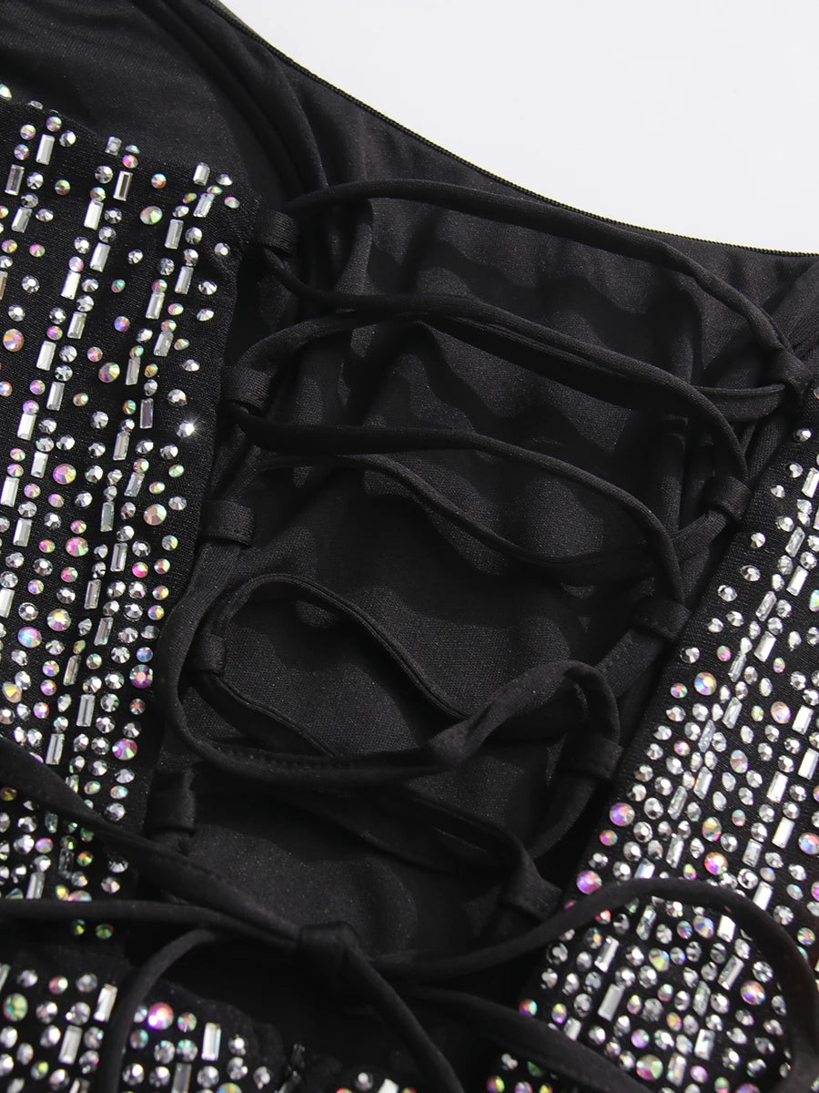 Black swimsuit with ruffled details and sparkling embellishments on a white background