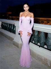 Woman in a pink strapless gown standing on a balcony at night.