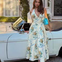 Woman wearing a mid-calf floral halter neck prairie chic dress with open back and dropped waist, styled for summer vacation