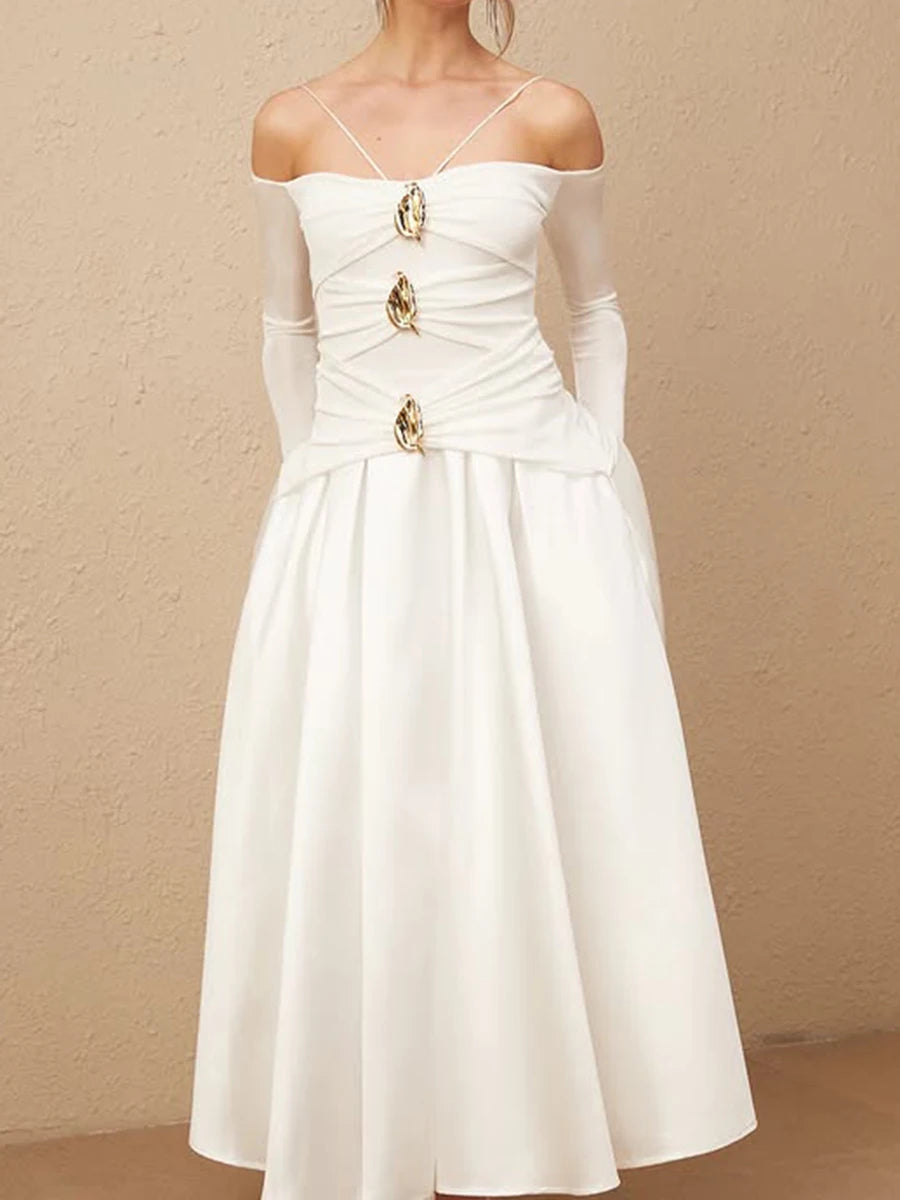 White dress with gold embellishments on a beige background