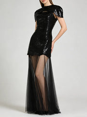 Black sequin mini dress with sheer tulle maxi overlay, model with hand on hip.