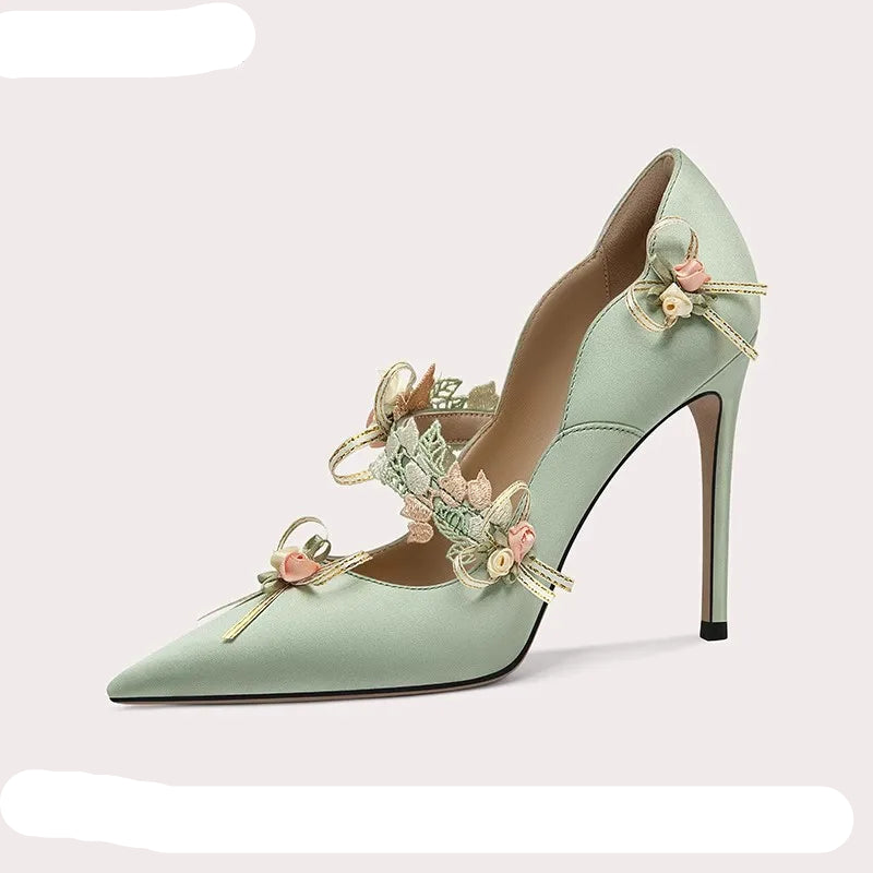 Mint green high-heeled shoe with floral decorations on a white background