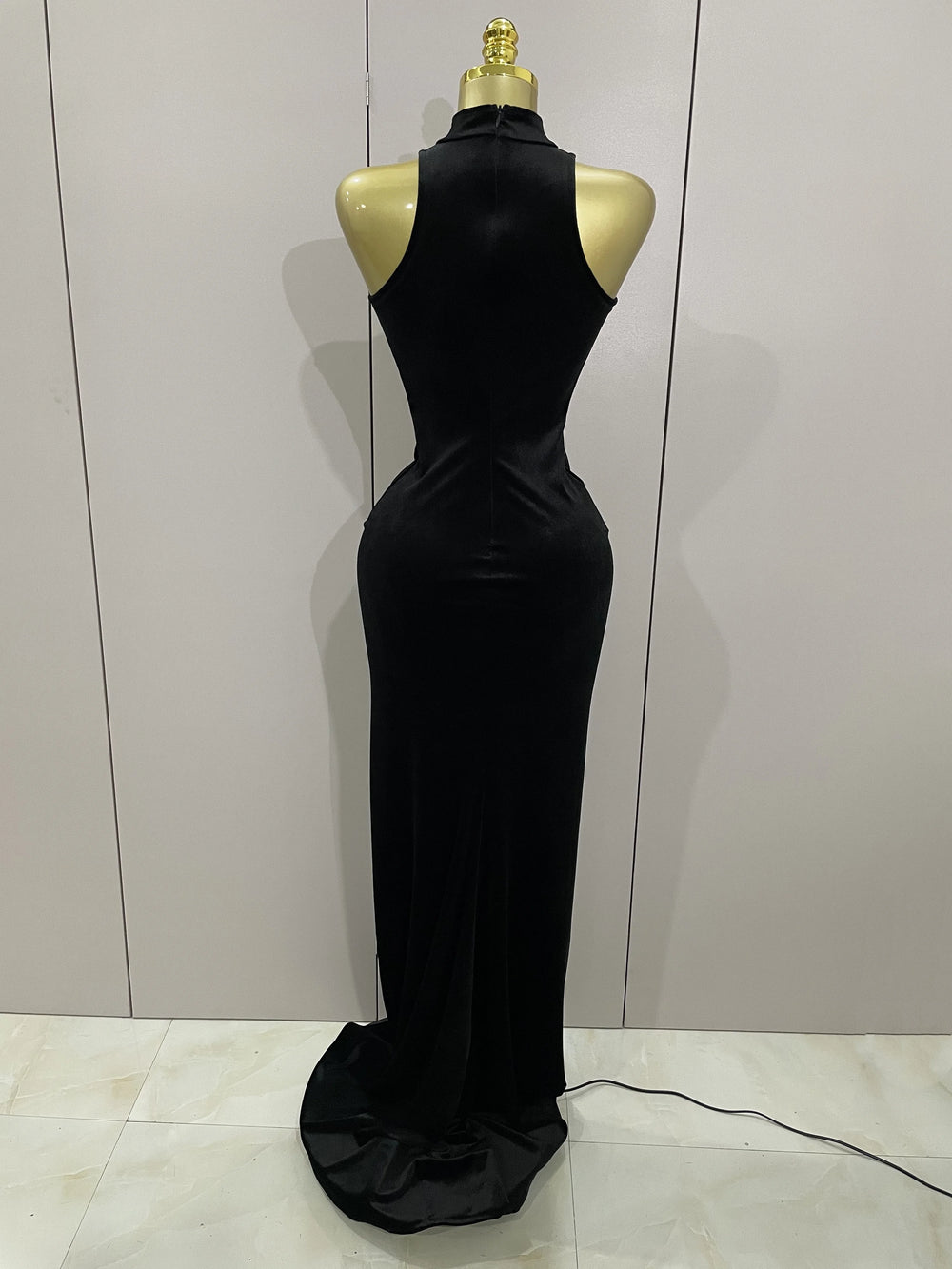 Black evening gown on a mannequin against a plain background