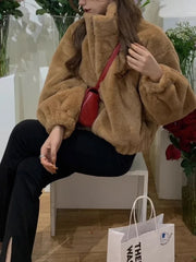 A woman wearing a stylish brown faux lamb fur coat with a zipper closure, posing in a winter setting. Golden Atelier 4