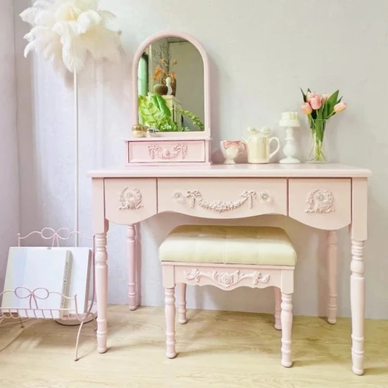 Pink vanity table with mirror and stool in a room setting
