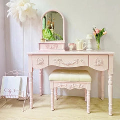 Pink vanity table with mirror and stool in a room setting