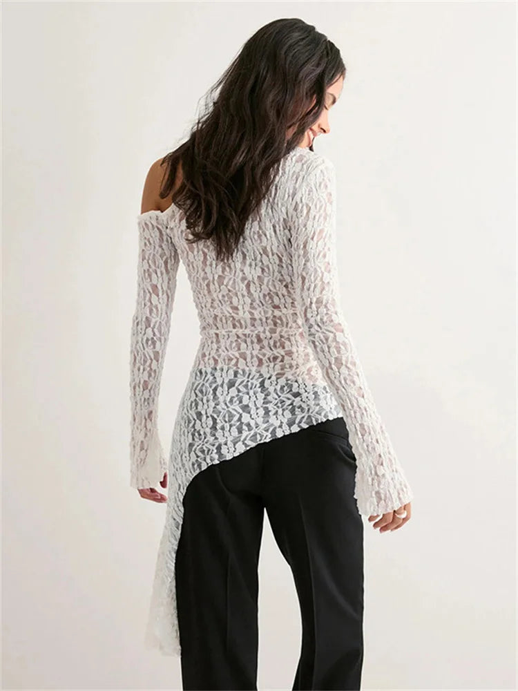 Woman wearing a white lace top and black pants on a plain background