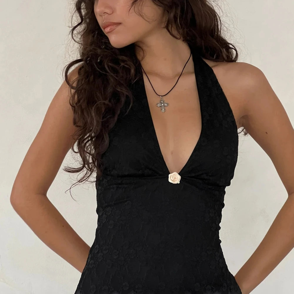 Woman wearing a black dress with a floral detail on a plain background