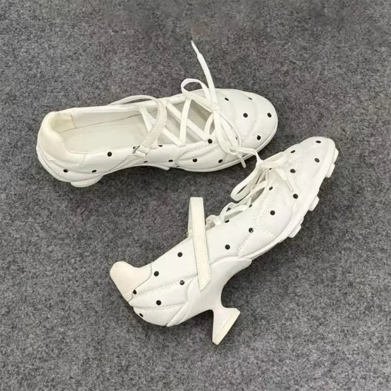 Detail shot of the sculptural heel on a white polka dot Mary Jane shoe.