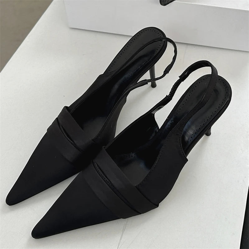 Black pointed-toe shoes with slingback design on a light gray background