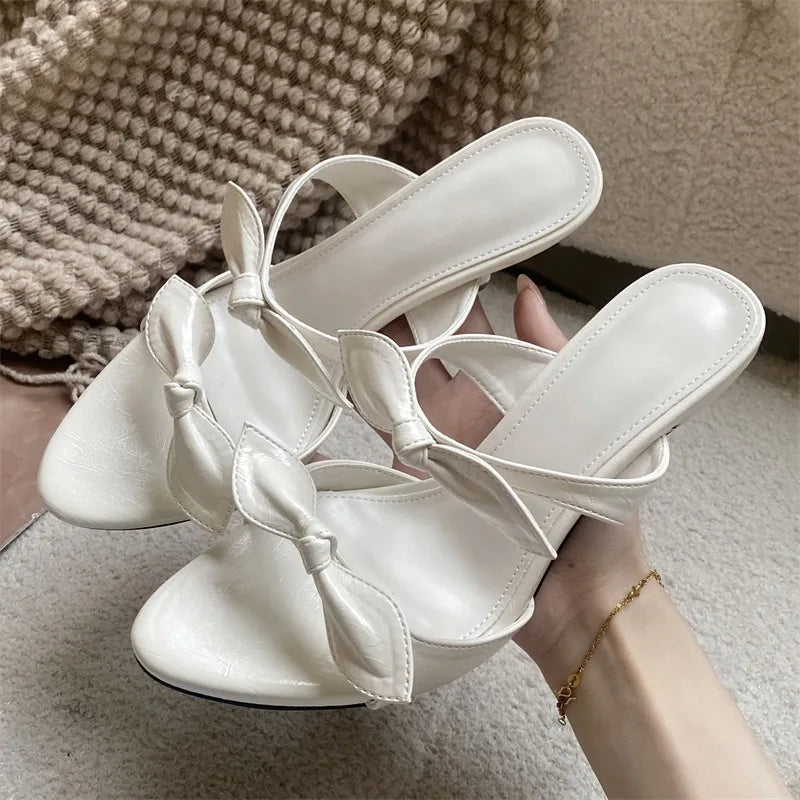 White pointed toe mules with a delicate bow detail