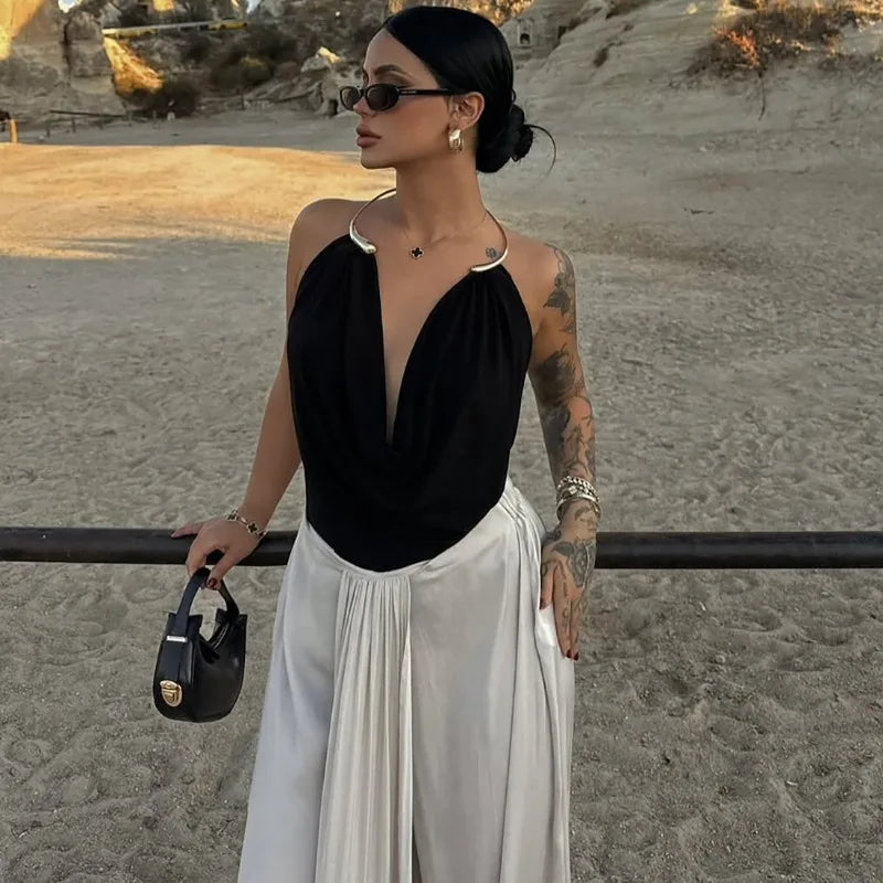 Woman in black top and white pants standing on a beach with a sunset in the background