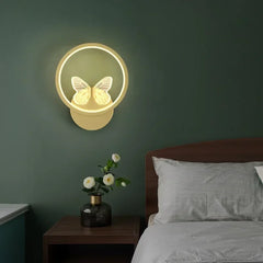 Decorative wall light with butterfly design on a green wall above a bed.