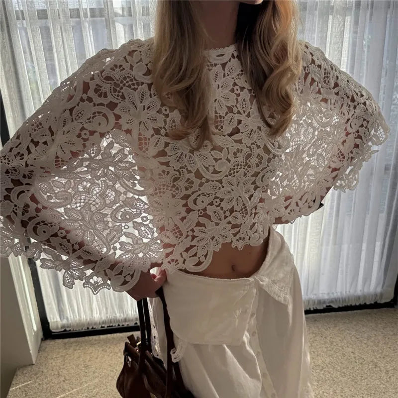 White cropped lace top with batwing sleeves worn with a white skirt.