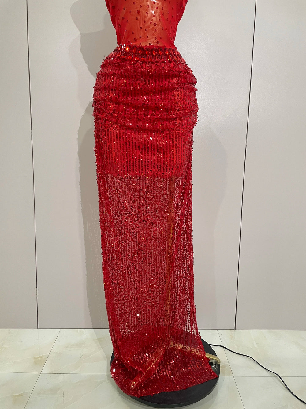 Red sequin dress on a mannequin against a white wall.