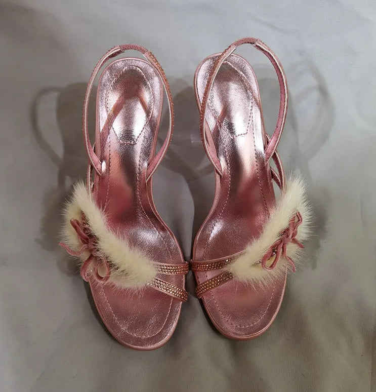 Top view of pink stiletto heels with faux fur bow accents