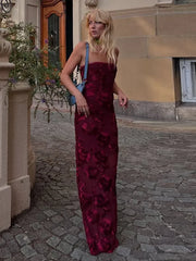Woman in a burgundy floral dress standing on a cobblestone street.