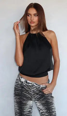 Woman wearing a black halter top and patterned pants against a white background