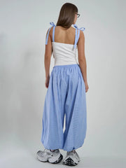 Woman wearing a white top and blue checkered pants on a plain background