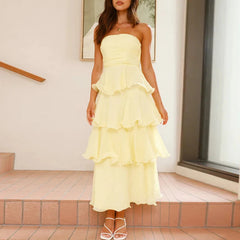 Woman wearing a yellow strapless dress with ruffled layers outdoors.