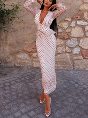 Woman in a polka dot dress posing against a stone wall.