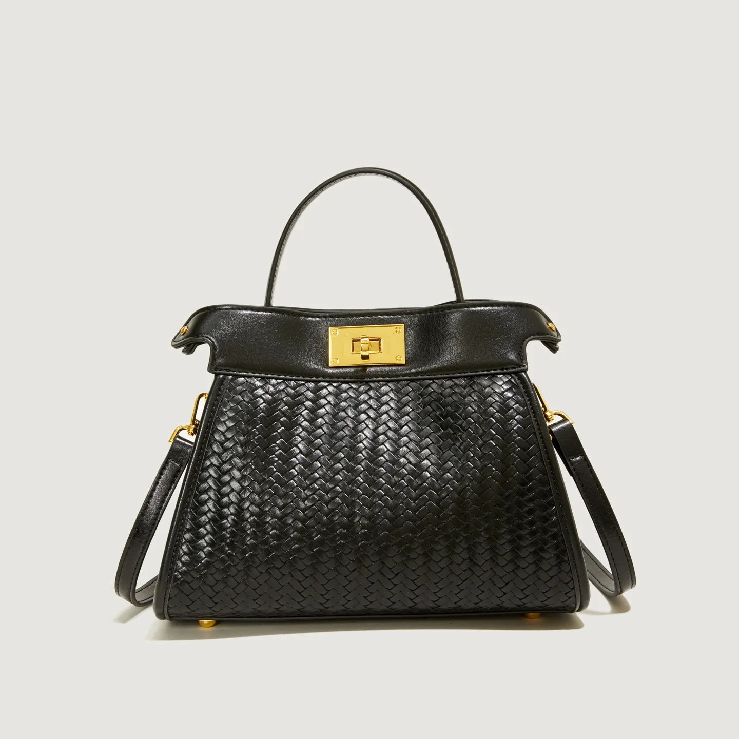 Black woven handbag with gold accents on a light gray background