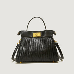 Black woven handbag with gold accents on a light gray background