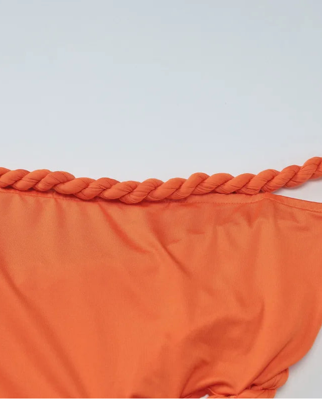 Orange bikini bottom with braided detail on a light gray background
