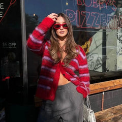 Woman wearing a red striped sweater and sunglasses in front of a pizza shop.