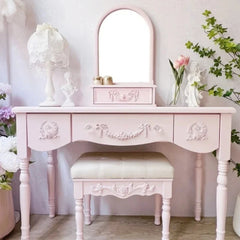 Pink vanity table with mirror and stool in a decorated room