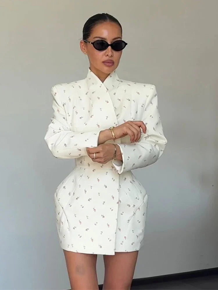 Person wearing a white patterned outfit with sunglasses against a plain background